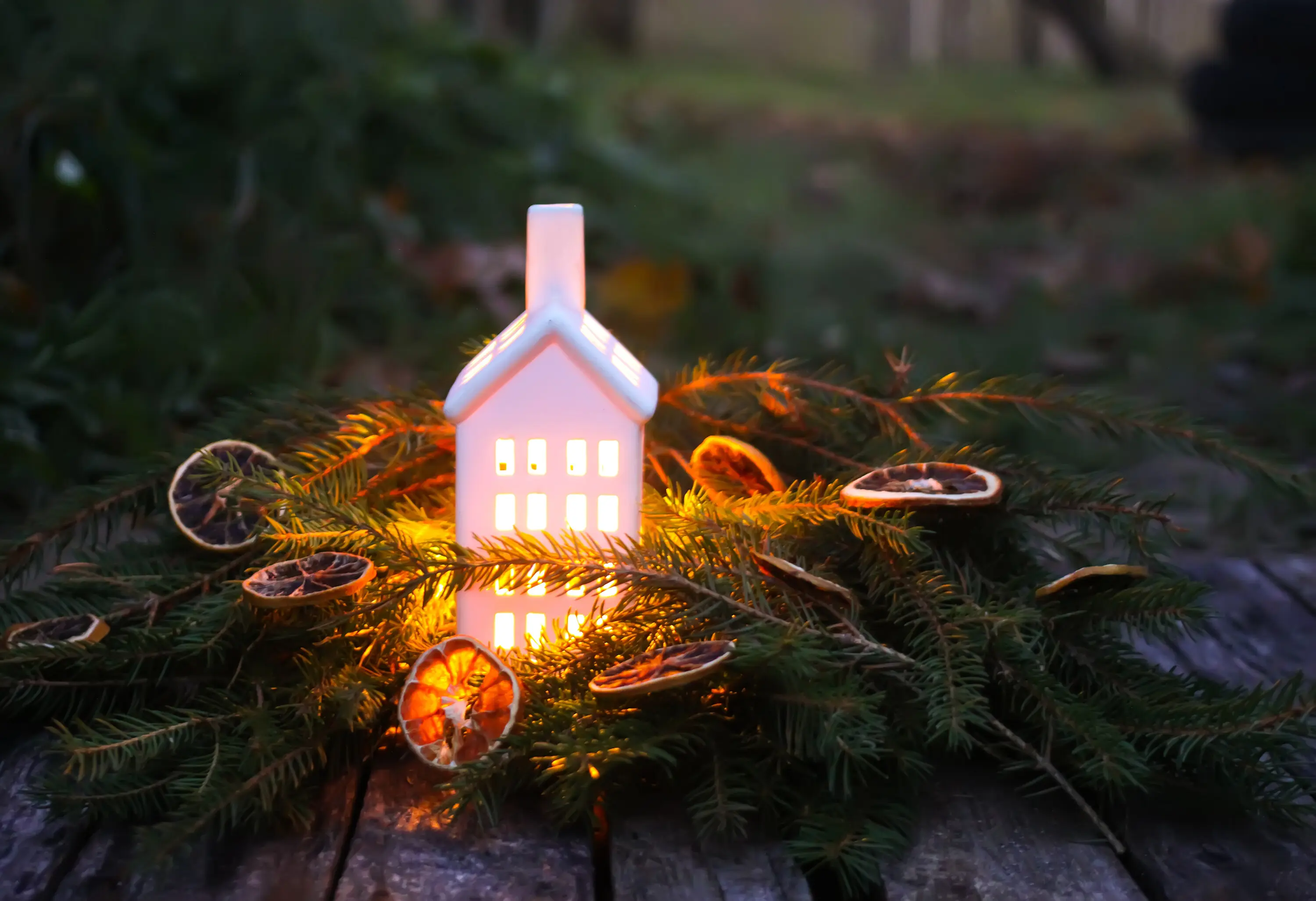 In an autumn park in the evening, a decorative house lantern holds a burning candle.